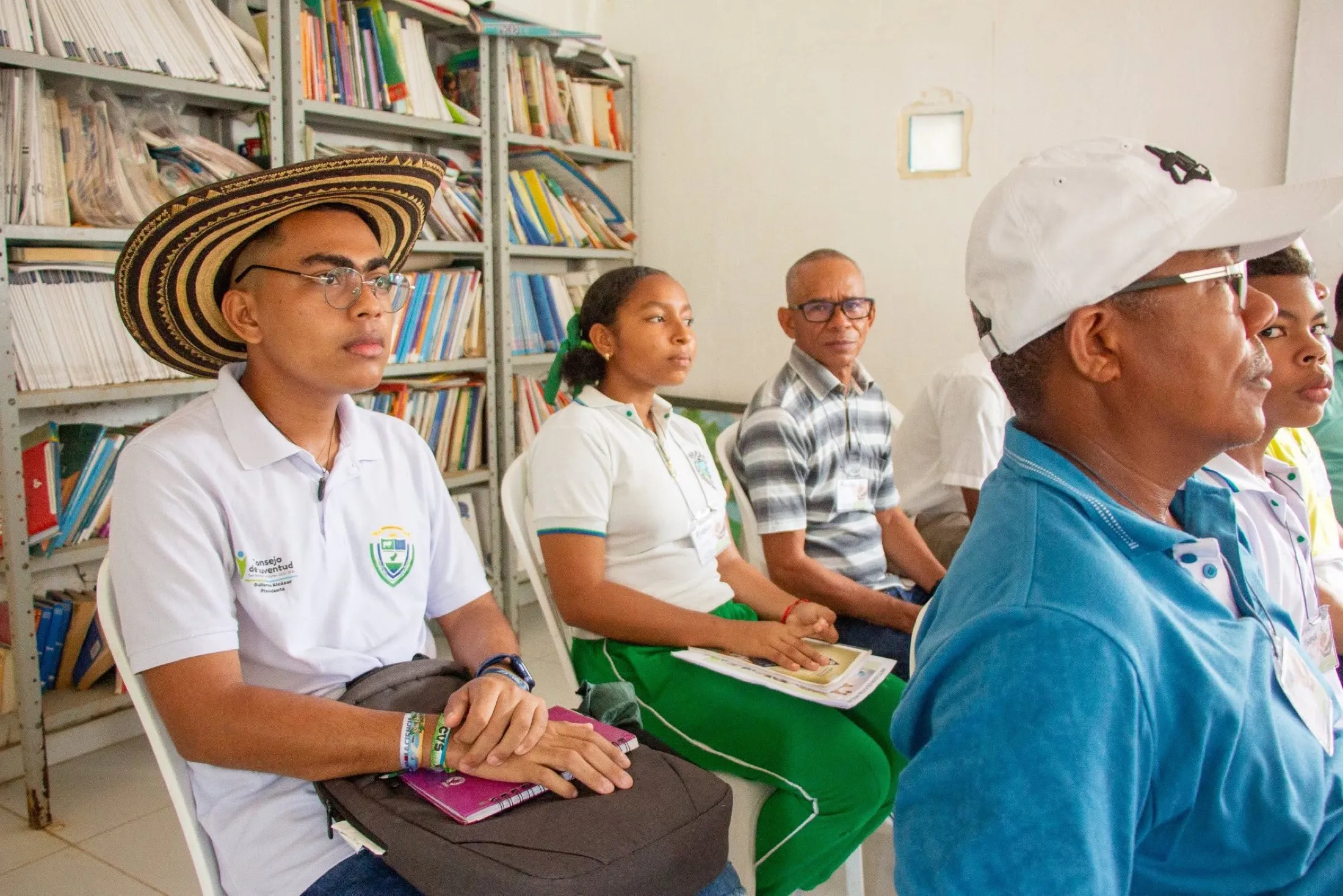Sabedores, familias y estudiantes de Paso Nuevo reunidos en la biblioteca de la institución